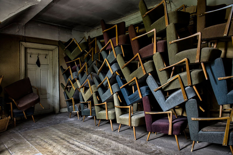 Old wooden chairs stacked on top of each other.