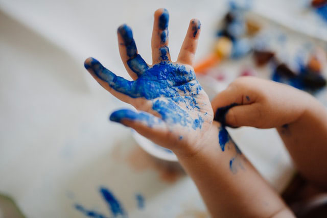 A child with blue paint on their hand.